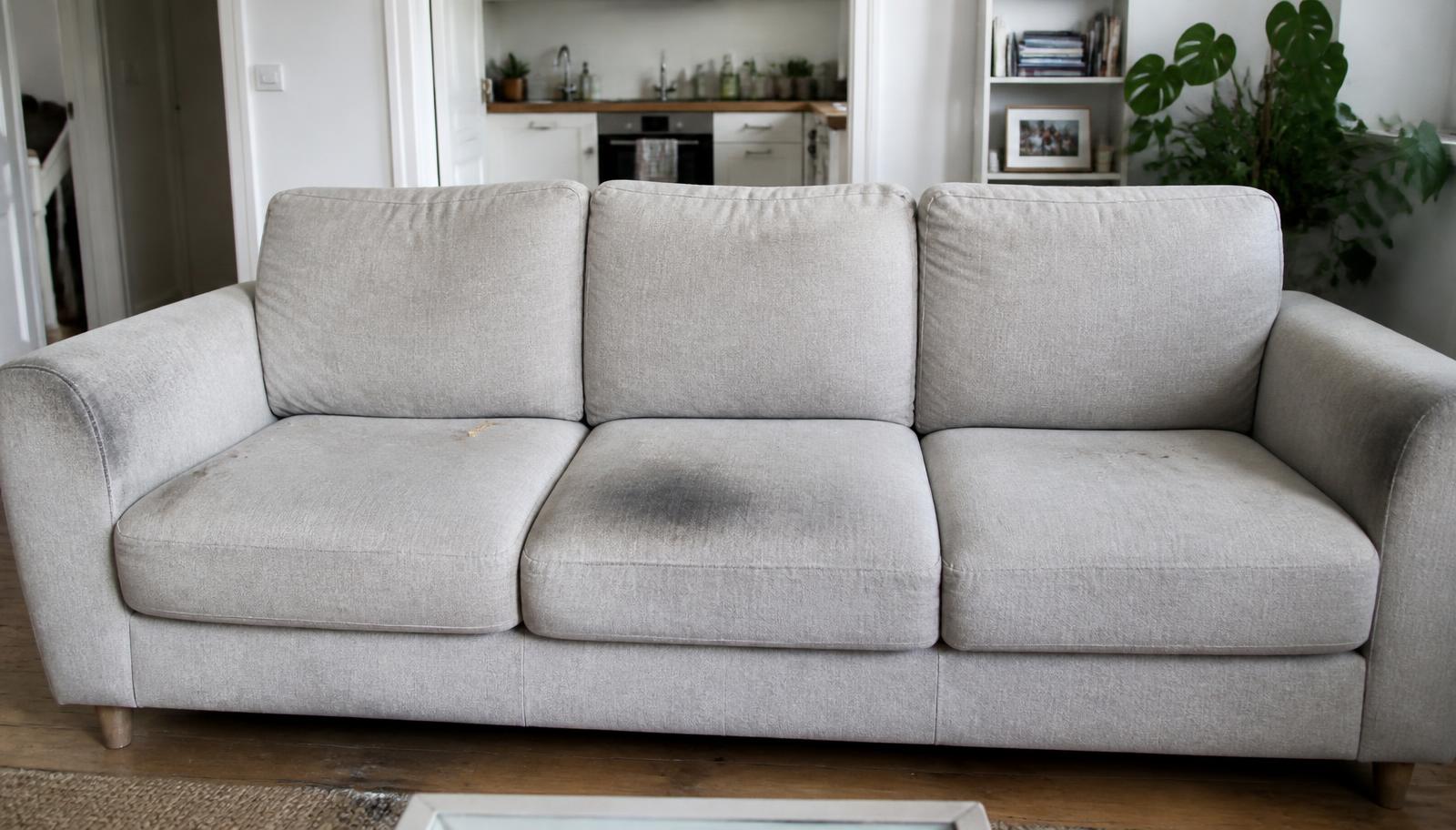Grey fabric sofa in Hackney before cleaning, with soiled armrests and a stain